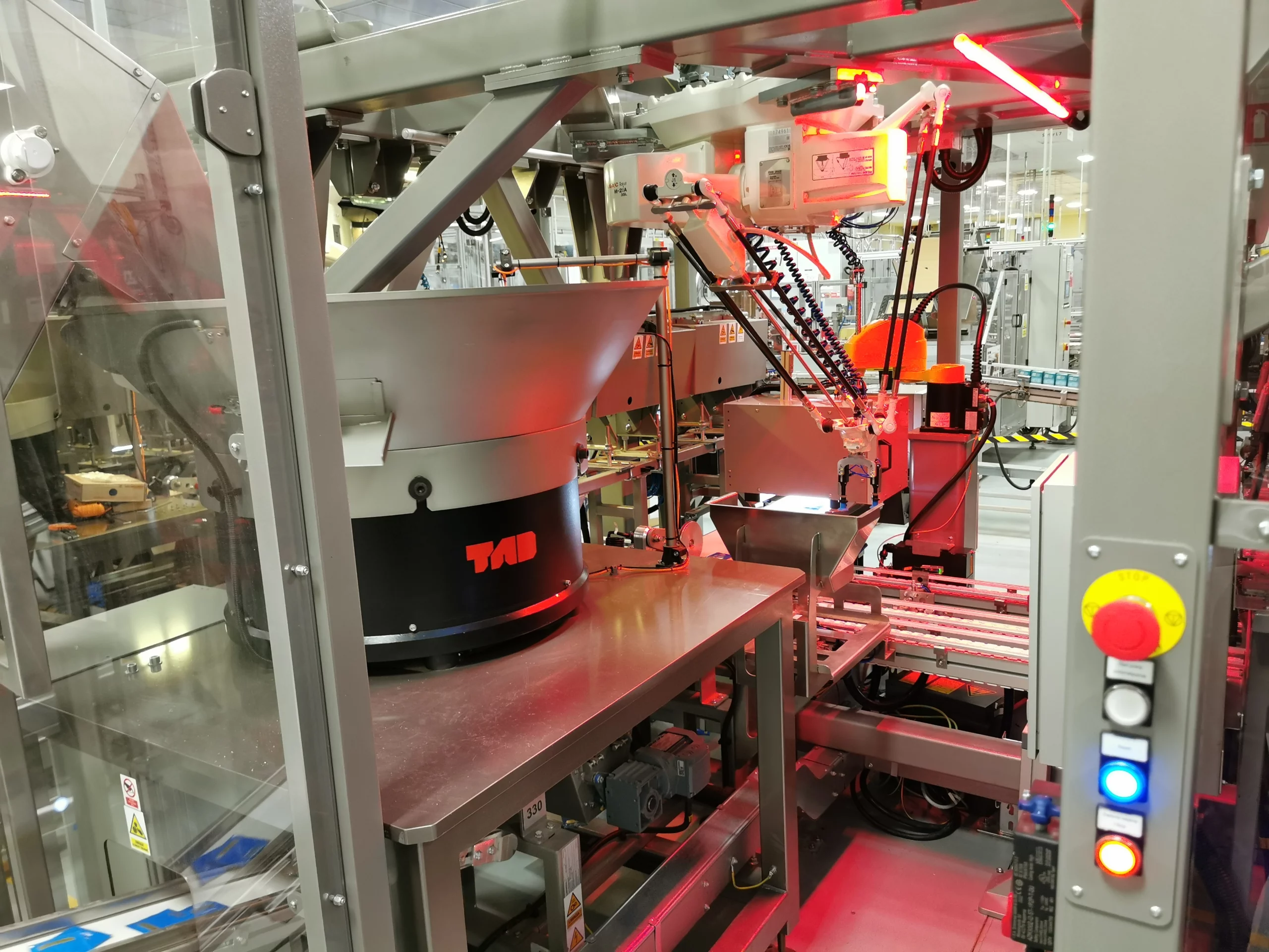 Gniazdo robotów Delta i SKARA w linii miksowania saszetek z herbatą w opakowaniach detalicznych. Roboty pozycjonują i pakują saszetki w zasobniki.