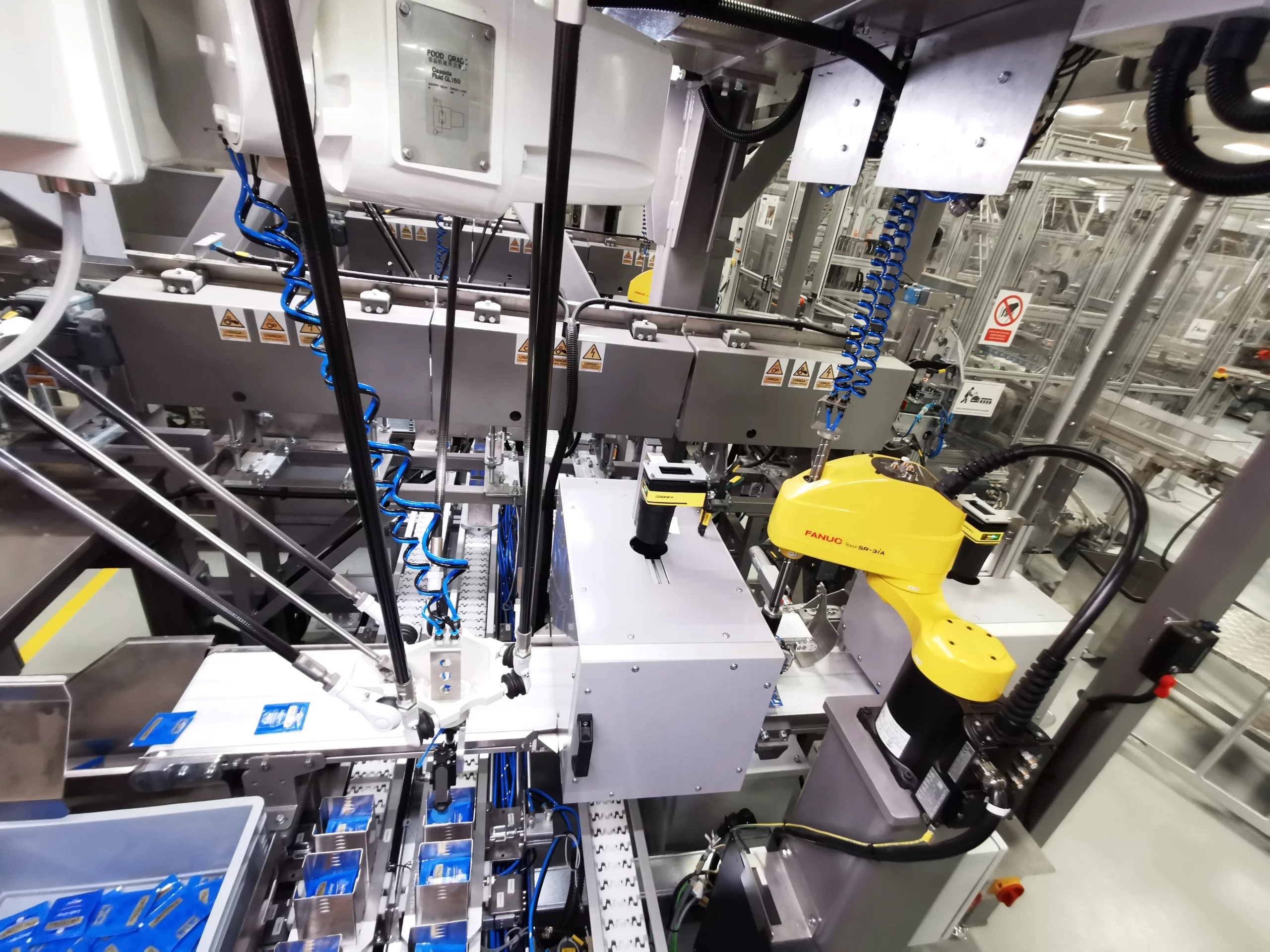 Robot SCARA pozycjonujący saszetki z herbatą oraz robot Delta umieszczający saszetki w zasobnikach, w których kompletowane są zestawy herbatek.