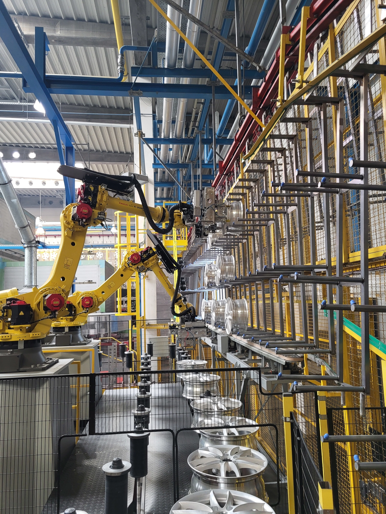 Dwa roboty przemysłowe FANUC przenoszą felgi aluminiowe w ramach zrobotyzowanej linii firmy Wikpol.