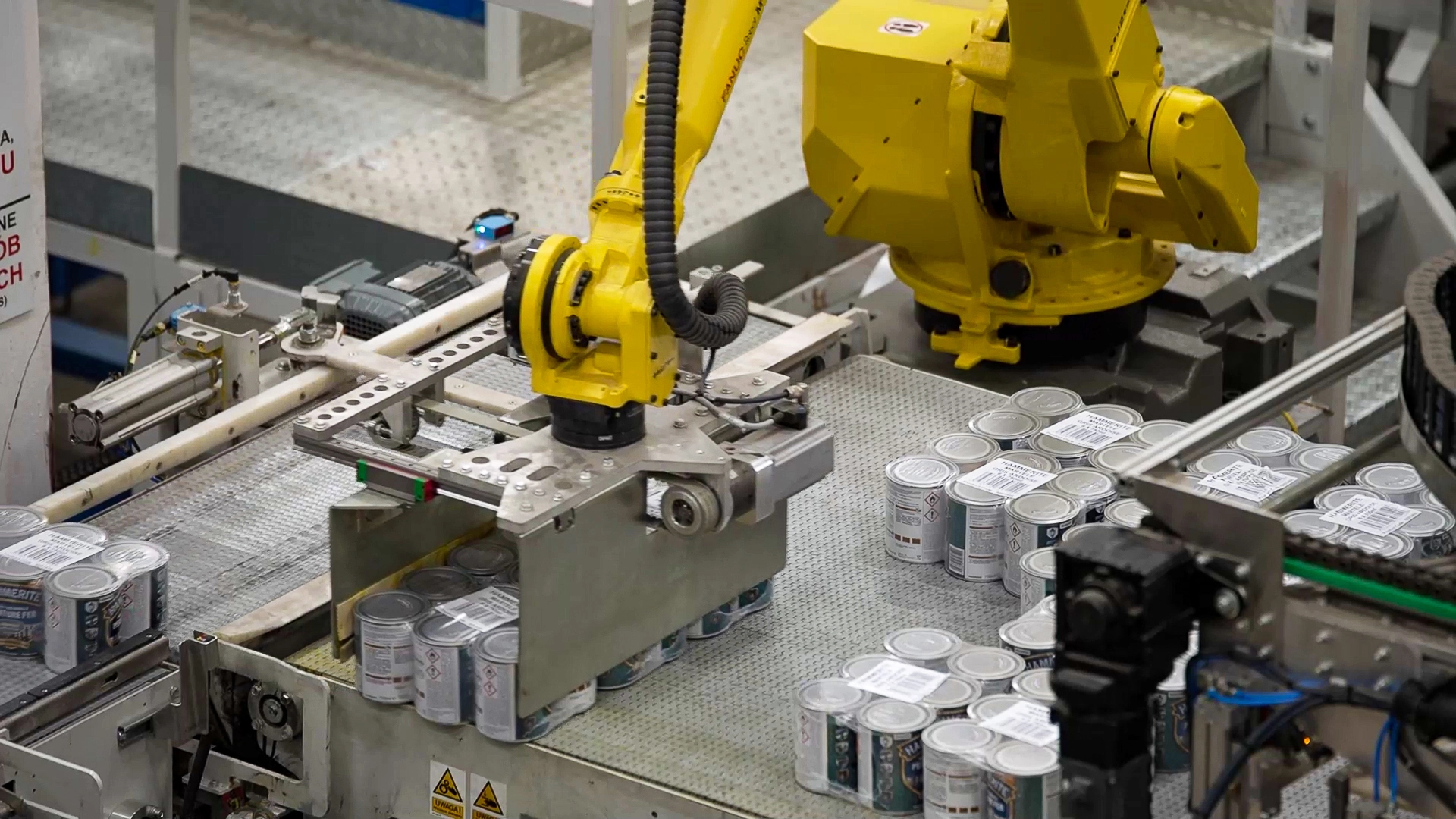 Robot przemysłowy kompletujący puszki z farbą przed paletyzacją – element zrobotyzowanej linii paletyzacji